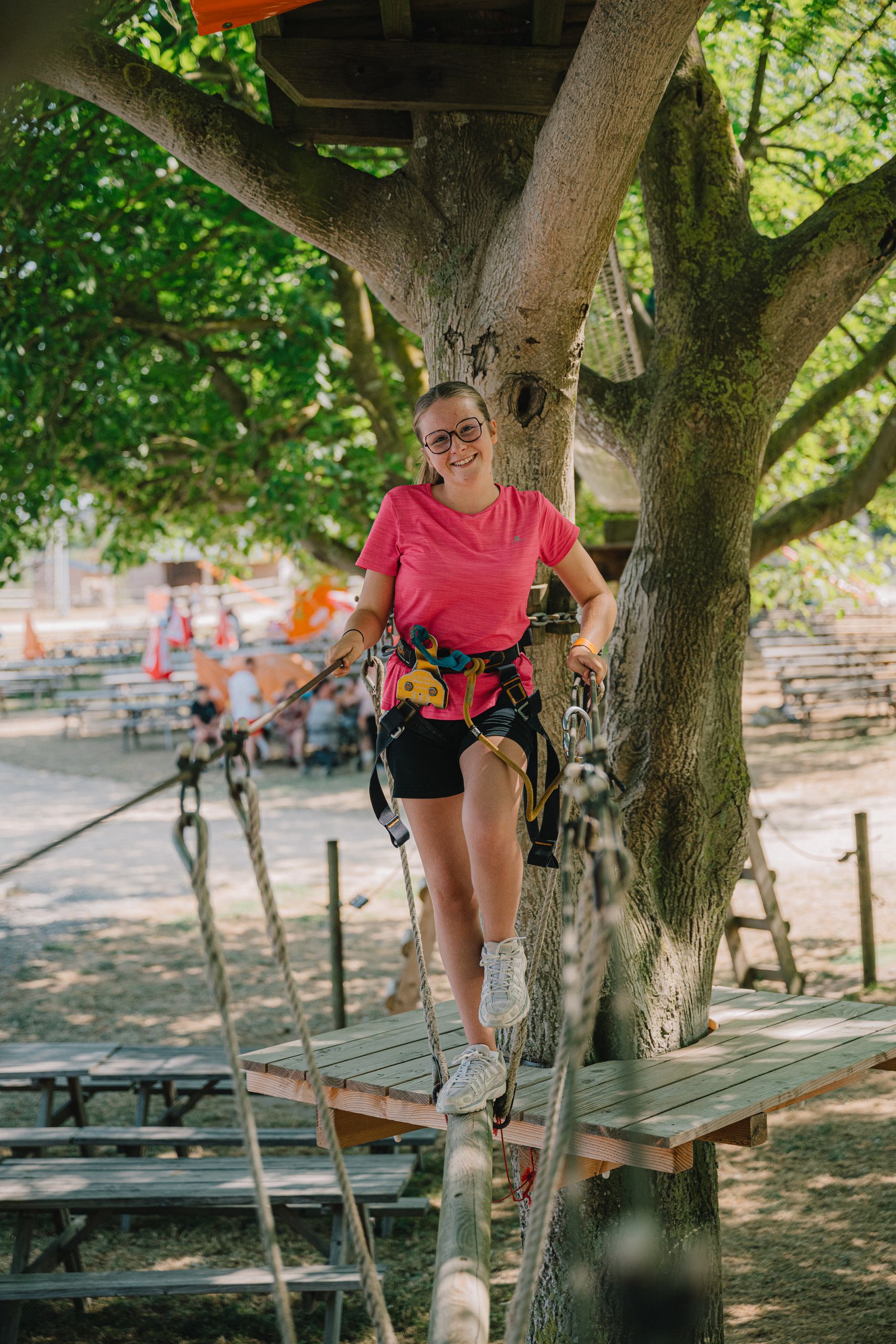 Une enfant équipée d'un baudrier sur un parcours d'accrobranche