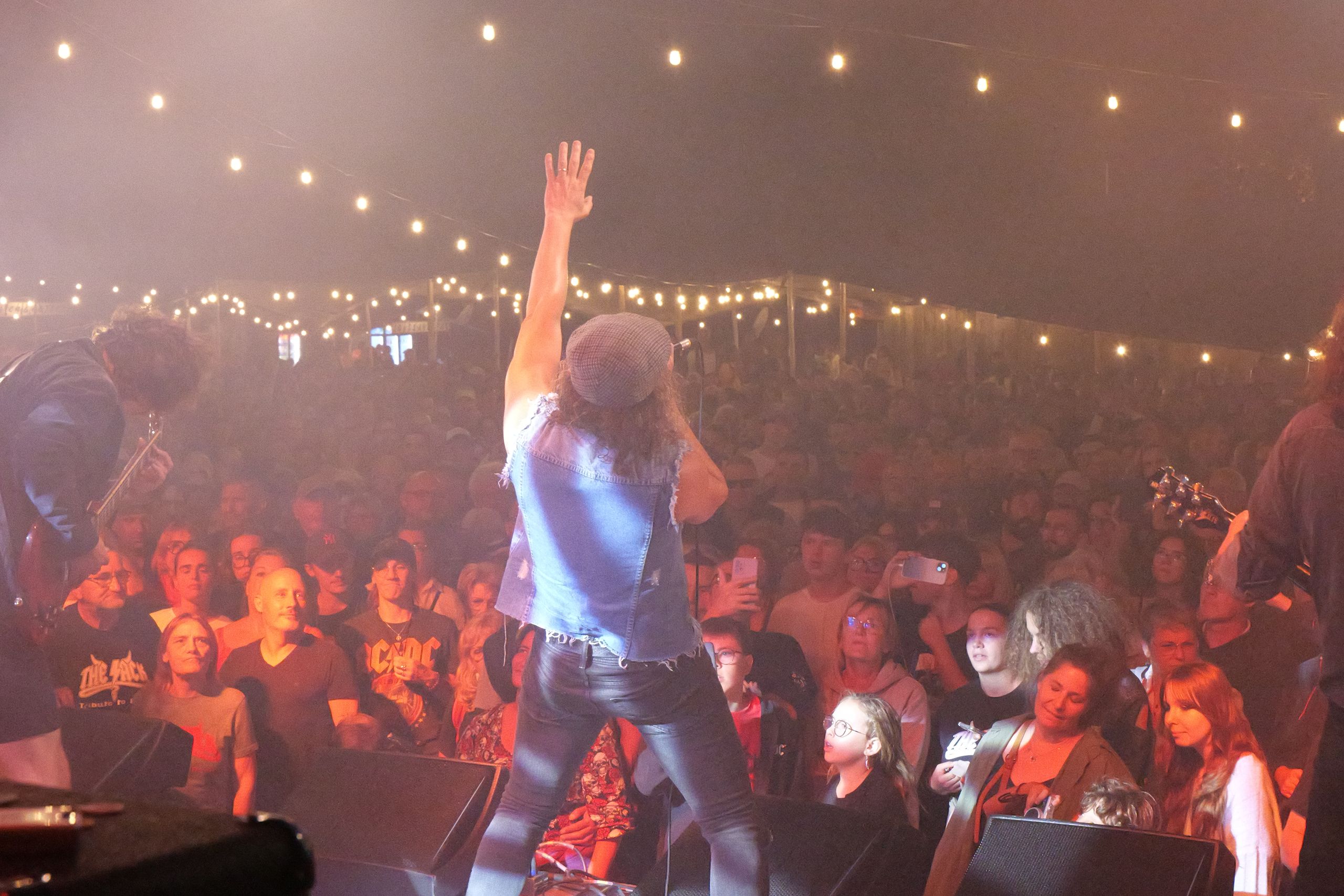 Chanteur bras levé devant une foule nombreuse