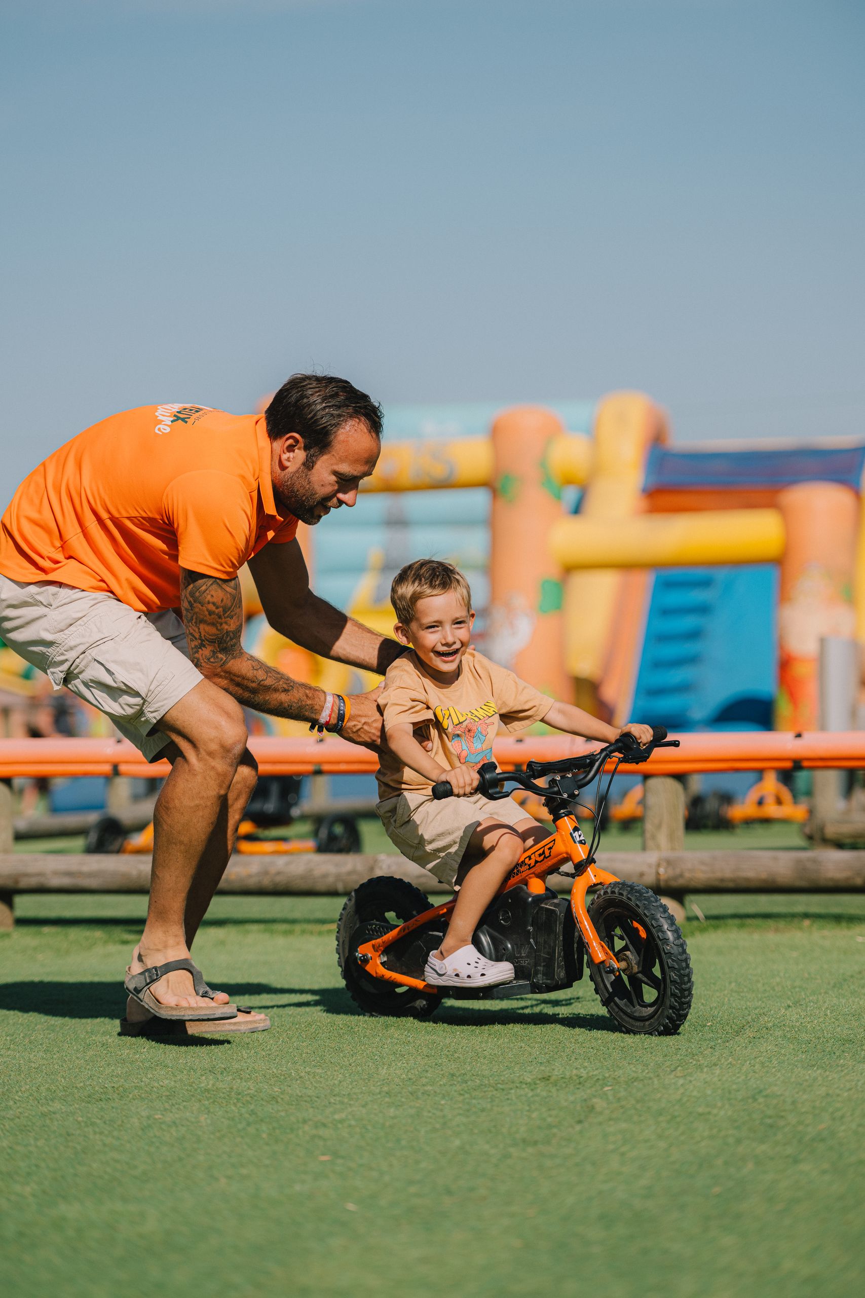 Un animateur encourage un enfant qui démarre en draisienne électrique