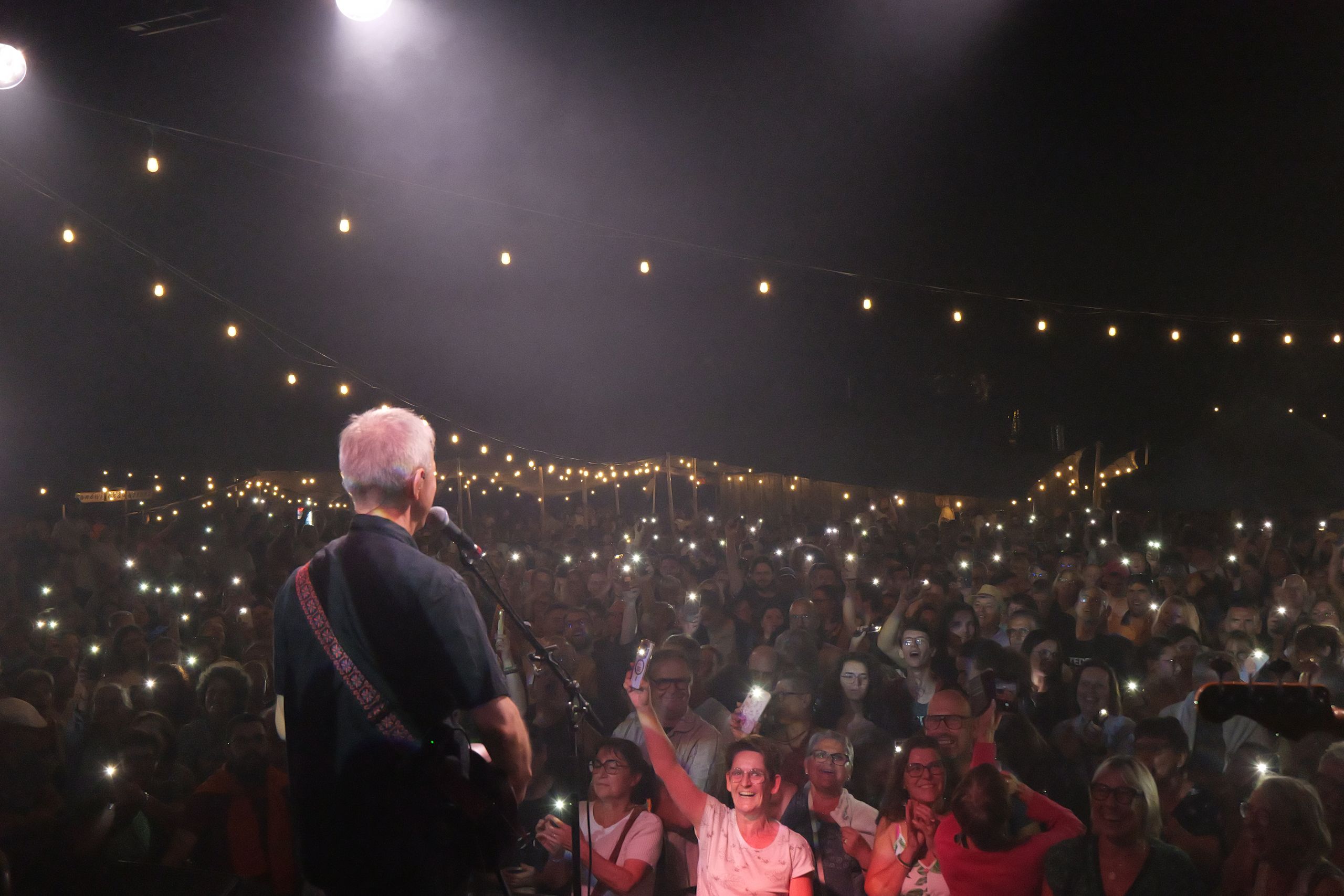 Guitariste face au public sous les guirlandes lumineuses