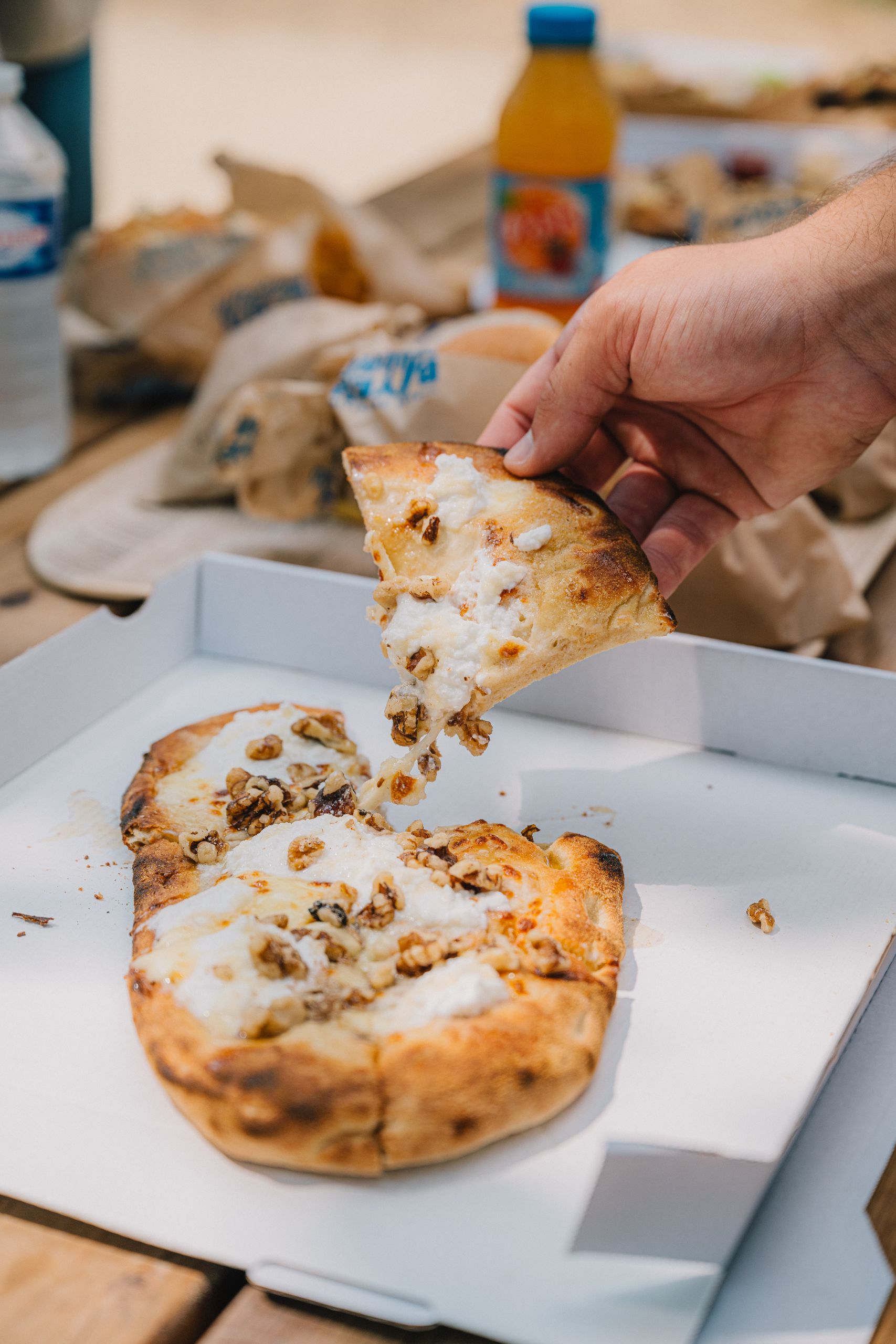 Une part de pizza de l’Aventure Café, servie sur une table de pique-nique