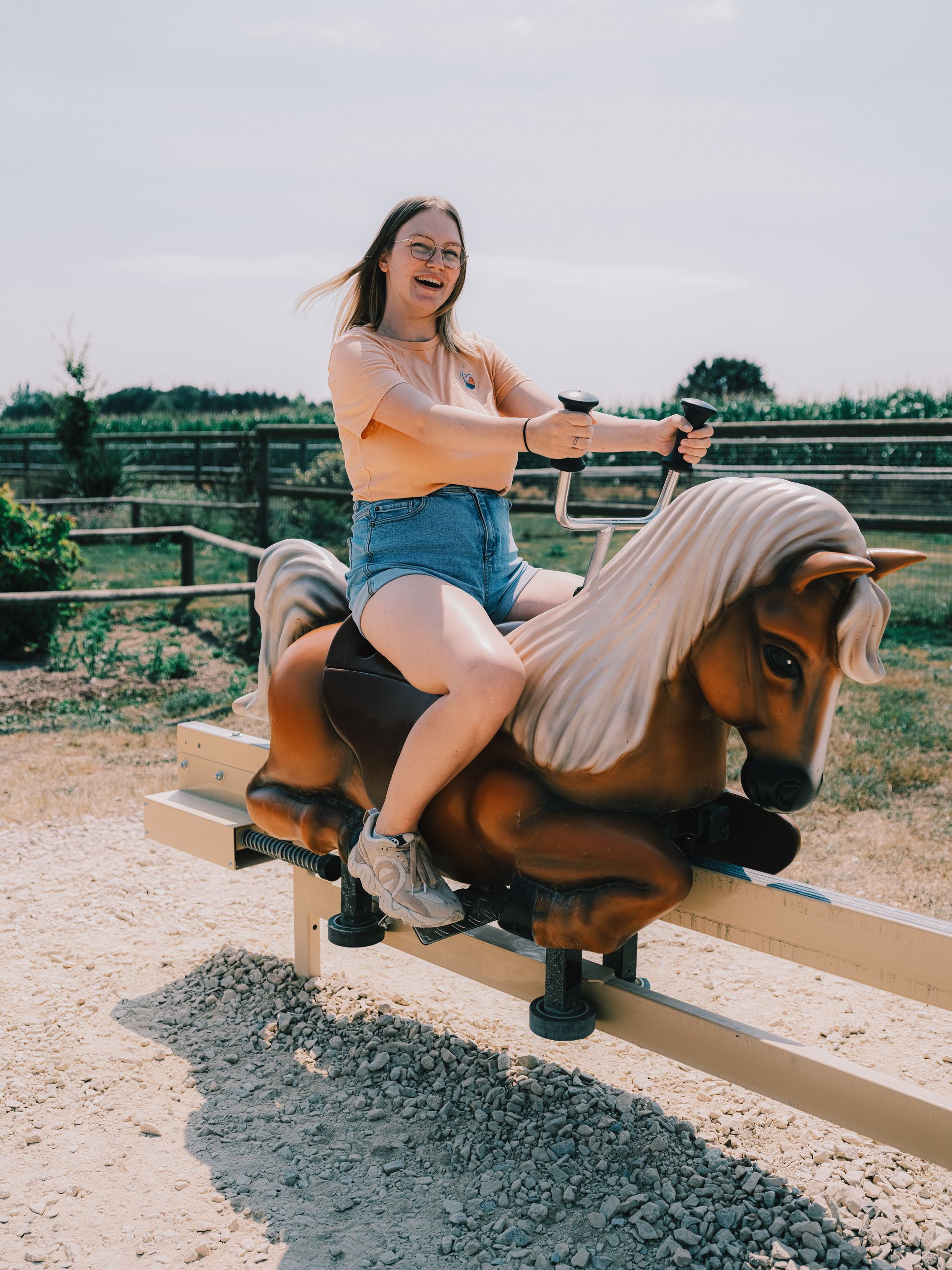 Une jeune femme éclate de rire sur un poney mécanique