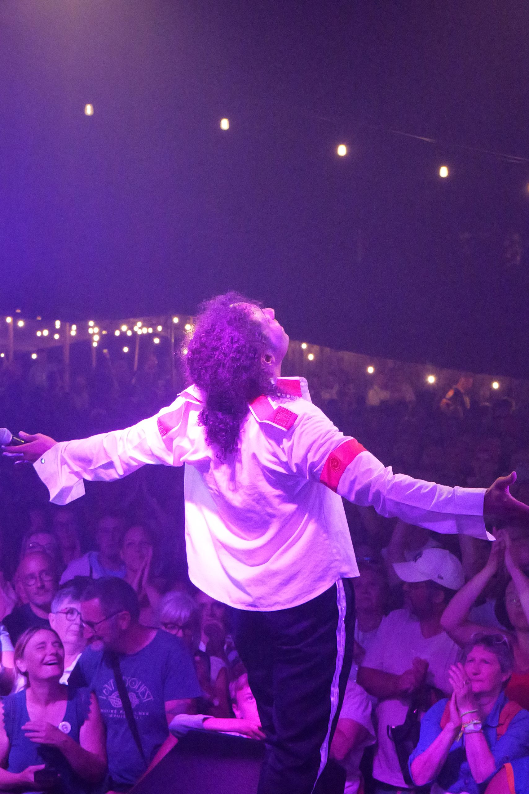 Artiste en blanc face au public lors d’un concert tribute