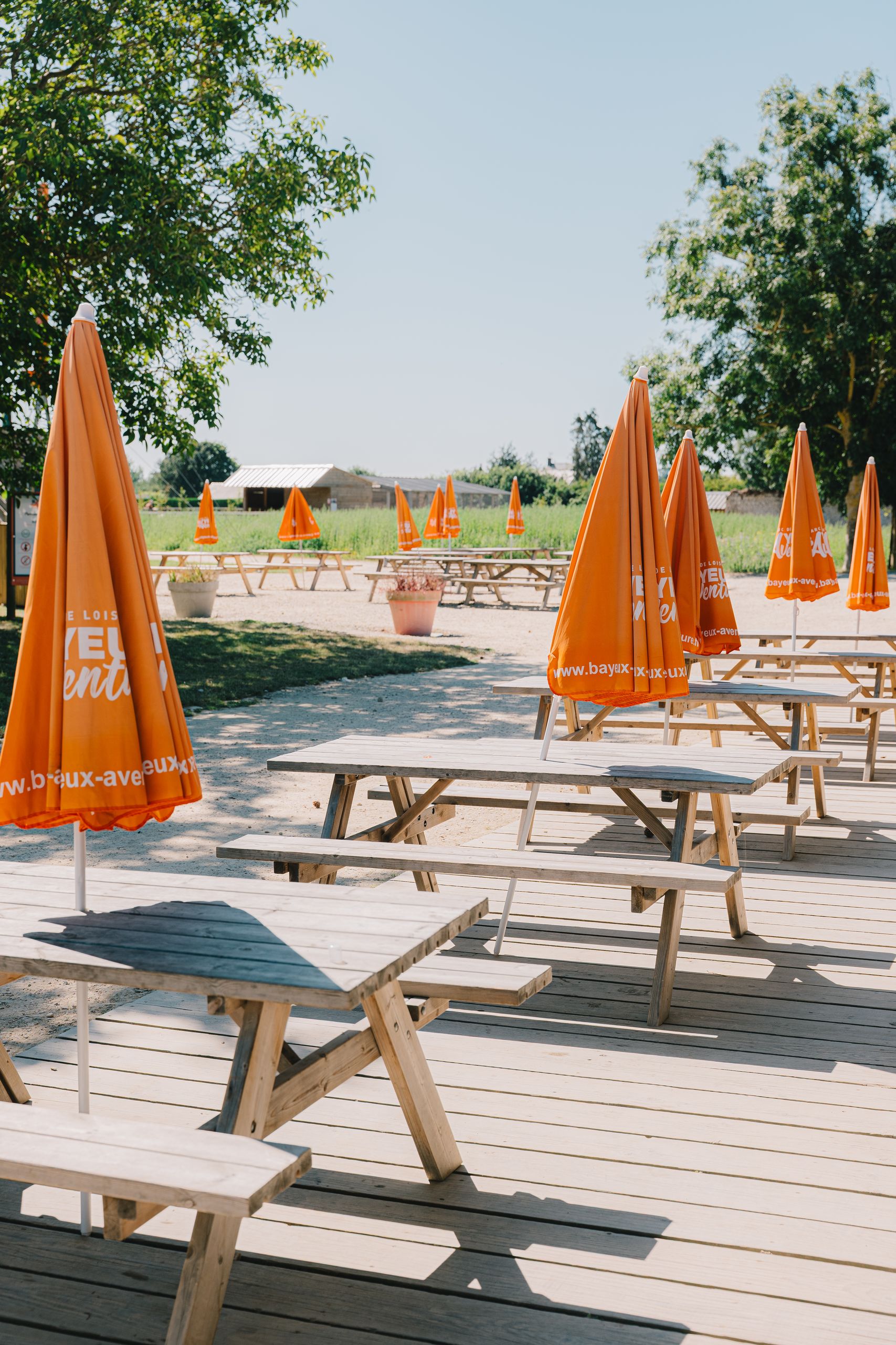 Terrasse avec tables en bois et parasols orange
